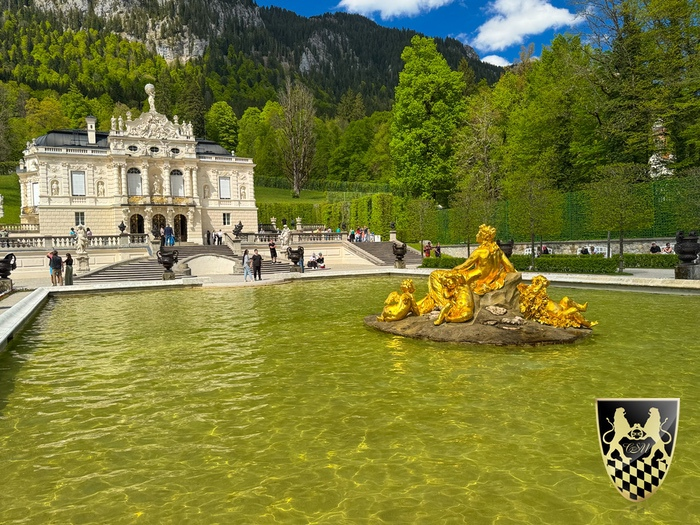 A stunning view of Linderhof Palace surrounded by lush gardens and the Bavarian Alps.