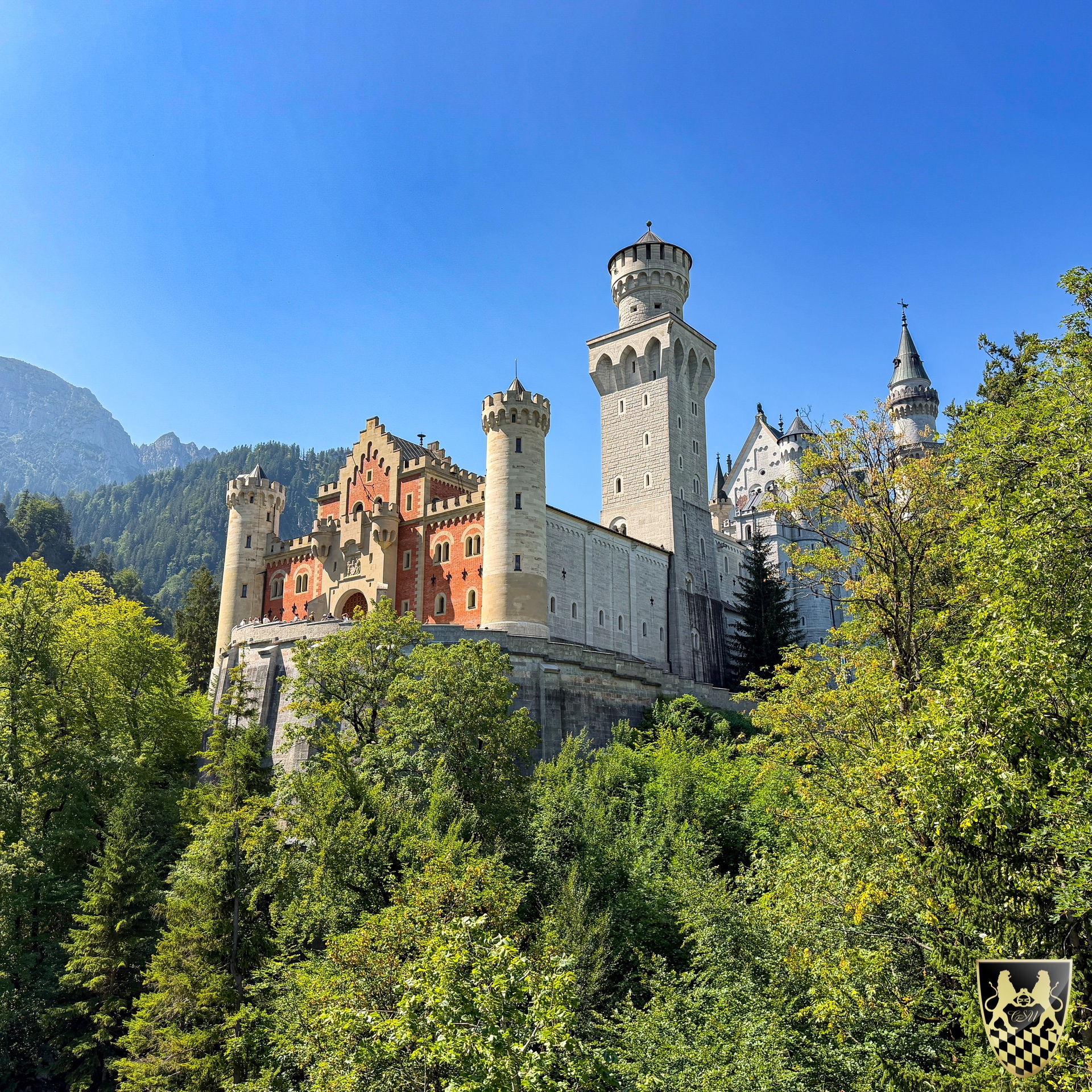 Neuschwanstein Castle with forested mountains in the background.