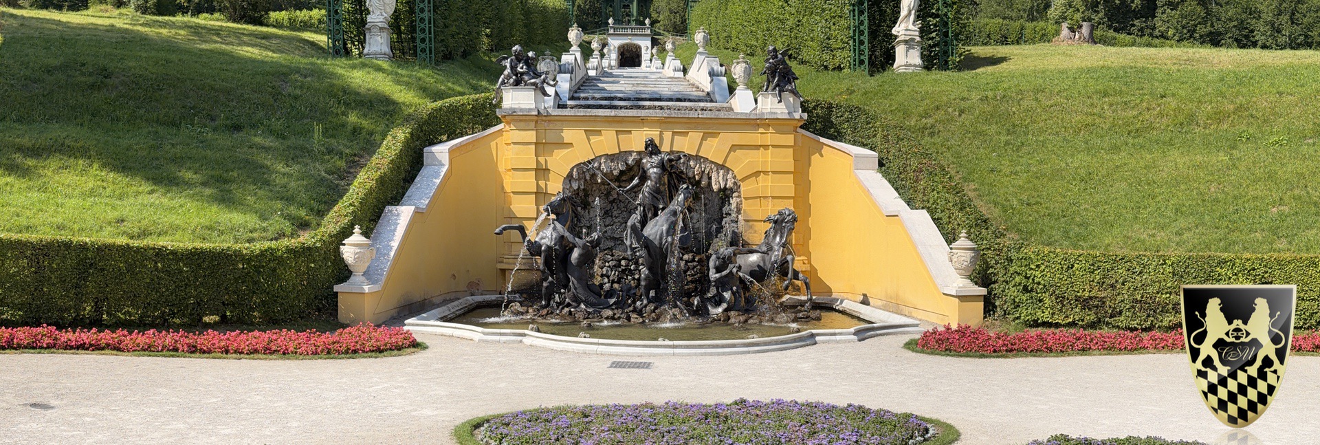 Ornate fountain with sculptures in a garden surrounded by greenery.