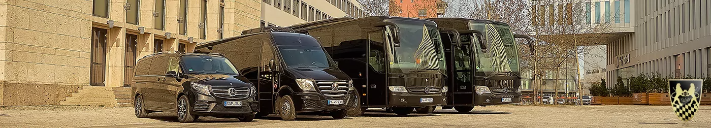 Three black Mercedes-Benz vehicles, including vans and buses, parked in front of a building.
