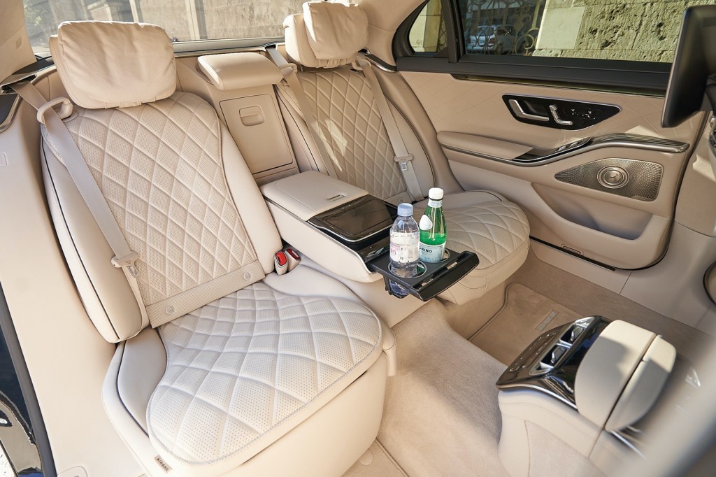 Luxurious car interior with beige quilted leather seats and bottled drinks in the center console.