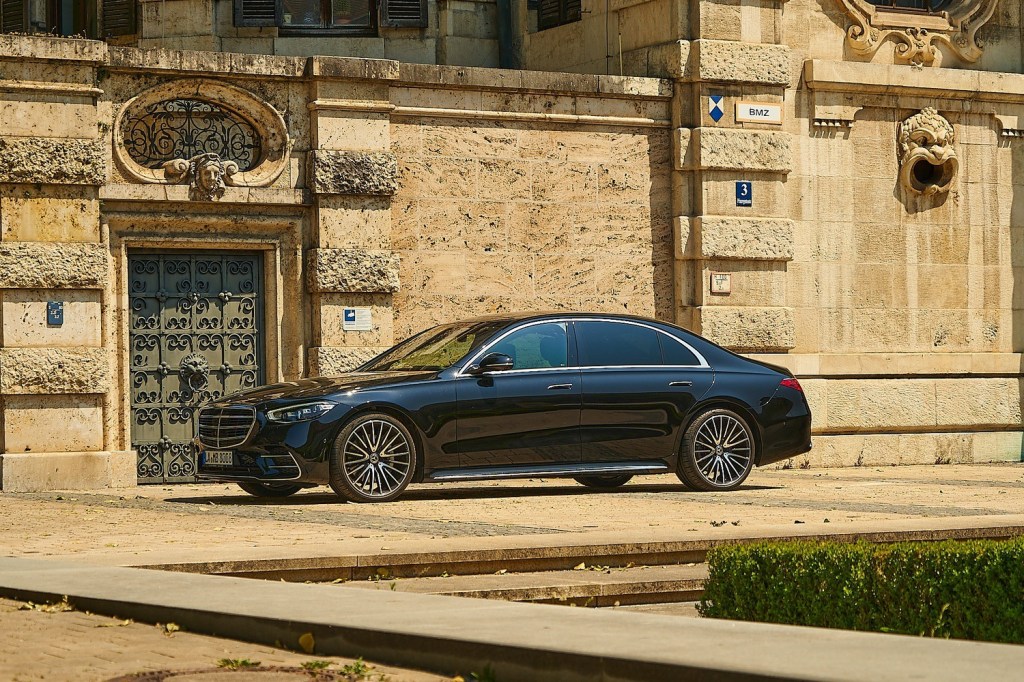 Black luxury car parked outside ornate stone building.